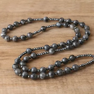 Detailed view of natural labradorite and hematite bead necklace on a light wood background