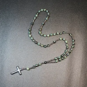 Detailed macro view of natural green jasper beads and hematite cross rosary necklace.
