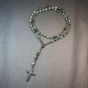 Detailed macro view of a natural sparrow stone rosary necklace with a metallic cross pendant