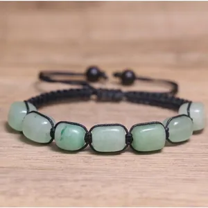 Primo piano dettagliato di perline in pietra naturale verde su un bracciale chakra nero regolabile