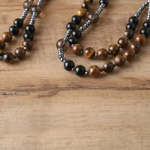 Close-up of natural tiger's eye and hematite beads on a textured wooden surface.