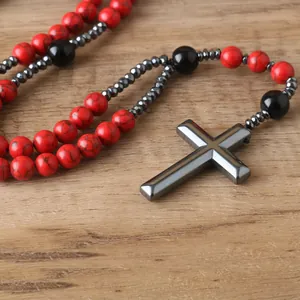 Close-up detail of hematite cross pendant on red and black beaded rosary necklace