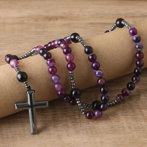 Close-up of beaded rosary necklace with purple agate and metallic cross pendant.