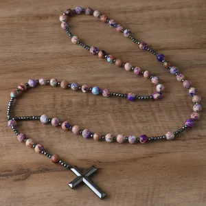 Detail of natural stone beads and hematite cross pendant on a rustic wooden surface
