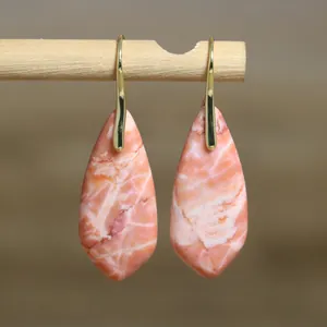 Close-up of elegant teardrop imperial stone earrings featuring natural pink patterns.