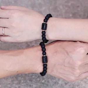 Primer plano de pulseras del zodiaco de cuentas de piedra negra mate para parejas.