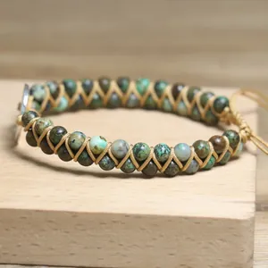Close-up of handmade double-layer woven African pine bead bracelet with charm.