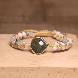Detail van een handgemaakte dubbellaagse labradoriet en agaat kralen geweven armband op hout