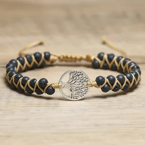 Close-up of silver tree of life charm and black lava beads on woven cord