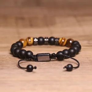 Close-up van verstelbare tijgeroog en zwarte matte kralenarmband op hout