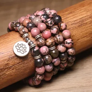 Dettaglio di un bracciale di perle di rodonite da 8mm con ciondolo a fiore di loto