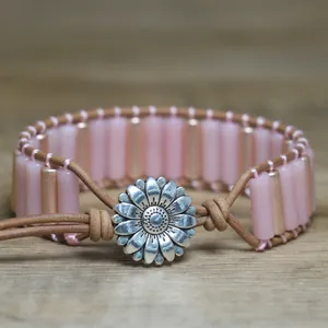 Close-up of handmade pink natural stone tube braided bracelet with silver sunflower clasp