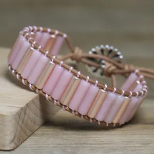Close-up view of a handmade woven adjustable bracelet with pink and gold beads.