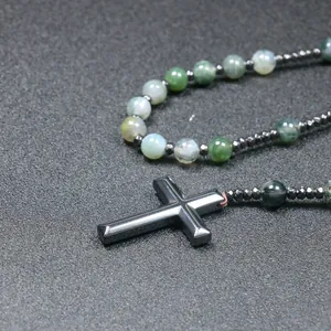 Detailopname van een natuursteen kralenketting met gepolijste zwarte hematiet kruis