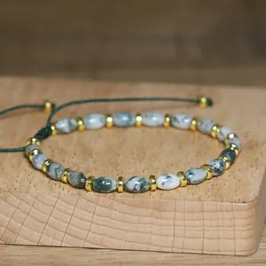 Close-up of handmade aquatic agate beaded bracelet with adjustable green cord