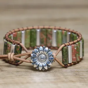Detail view of handmade woven leather bracelet featuring green stone and silver daisy button.