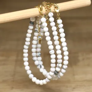 Close-up view of white howlite stone bead necklaces with adjustable gold chain