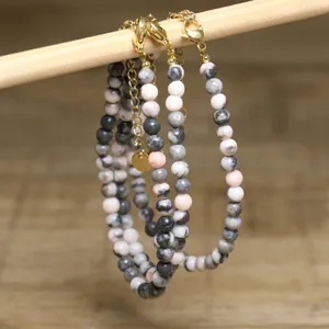 Macro view of handmade pink and grey stone beaded necklace with adjustable gold chain