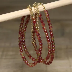 Close-up of handmade round bead necklace with gold extension chain and lobster clasp.