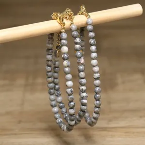 Detailed view of grey marbled stone bead necklaces hanging on a wooden stick display