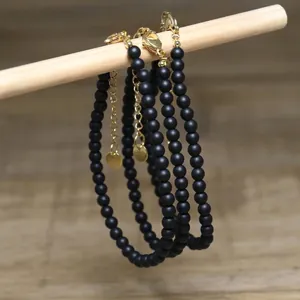 Close-up of matte black beaded necklaces with gold-tone extender chains