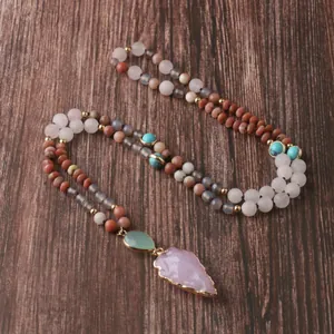 Détail du collier mala en quartz rose avec un pendentif pointe de flèche rose doré.