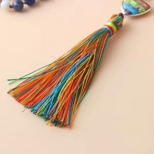 Détail de pompons en soie colorés sur un pendentif de collier Mala de yoga bohème.