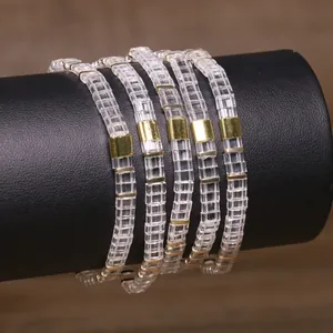Macro view of handmade Tila bead bracelets featuring clear glass and gold square spacers
