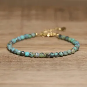 Detailed view of faceted turquoise stone beads on an adjustable gold chain bracelet