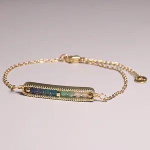 Close-up detail of a gold-plated link bracelet featuring a bar pendant with colorful beads