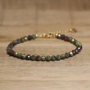 Detailed view of faceted African pine beads and adjustable gold chain on a wooden base.