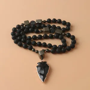 Primer plano de un colgante de punta de flecha de obsidiana en collar de lava