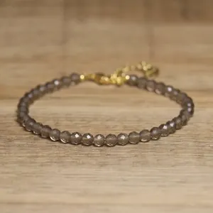Detail view of a faceted smoky natural stone beaded bracelet with gold clasp.