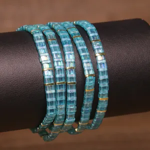 Close-up of handmade Tila bracelets with light blue beads and gold metallic spacers.
