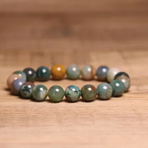 Close-up detail of 8mm natural Indian agate beaded bracelet on a rustic wood surface