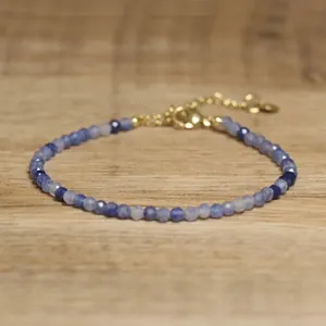 Close-up of handmade natural stone bracelet with faceted blue beads and gold clasp