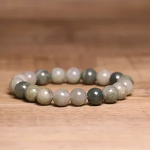 Macro detail of an 8mm natural Indian Agate beaded bracelet on a smooth wood surface