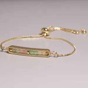Detailed view of a gold-plated adjustable bracelet with beaded rectangular bar pendant.