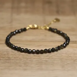 Close-up of faceted dark natural stone beads on a delicate adjustable gold bracelet