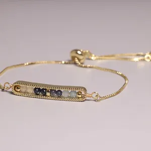 Detailed view of a gold-plated adjustable bracelet with multi-color stone beads in a bar setting