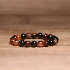 Detailed close-up view of 8mm natural Indian Agate beaded bracelet on wooden surface