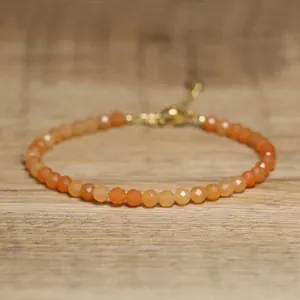 Close-up of faceted orange natural stone beaded bracelet with adjustable gold clasp