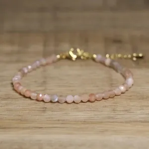 Close-up of faceted natural stone beaded bracelet with golden adjustable clasp on wood.
