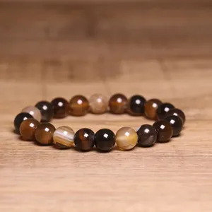 Macro shot of 8mm natural Indian agate beaded bracelet on a warm wooden background.