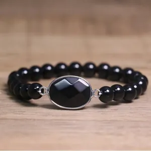 Détail rapproché d'un bracelet de perles noires avec pierre centrale ovale facettée