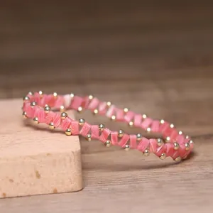 Handcrafted pink beaded elastic bracelet with striated textures and gold accents