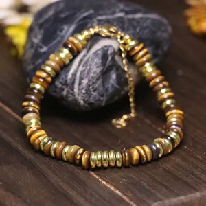 Dettaglio ravvicinato di perle occhio di tigre e distanziatori dorati su bracciale regolabile.