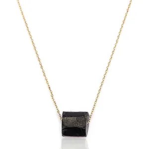 Primer plano de un collar minimalista con un colgante de piedra natural negra irregular