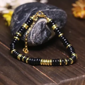 Primo piano del bracciale con grani abaco neri e dorati e catena regolabile in acciaio.