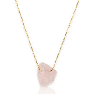 Detalle de colgante de cuarzo rosa natural irregular en cadena de acero inoxidable dorada